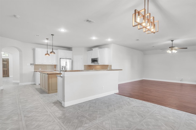 kitchen featuring decorative light fixtures, tasteful backsplash, a kitchen island, white cabinets, and appliances with stainless steel finishes