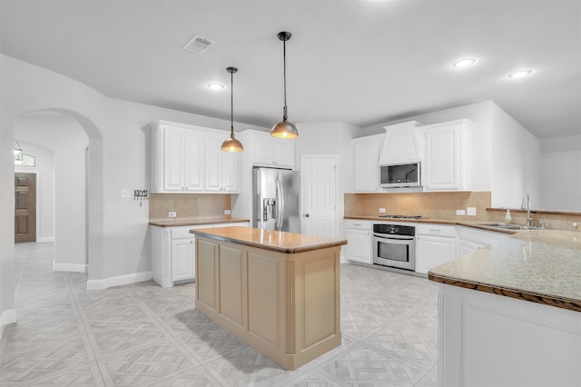 kitchen with sink, stainless steel appliances, white cabinetry, and pendant lighting