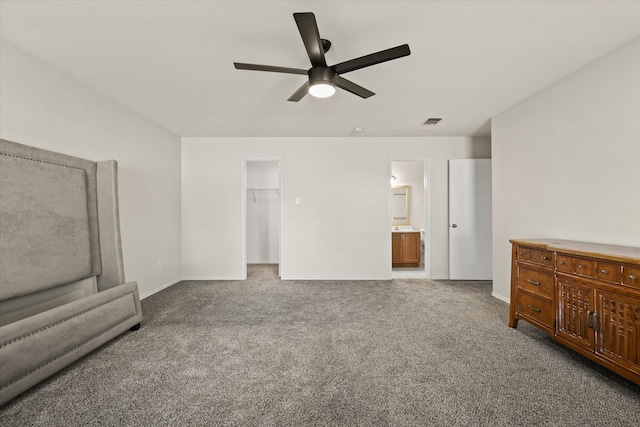 carpeted bedroom with connected bathroom, a walk in closet, a closet, and ceiling fan