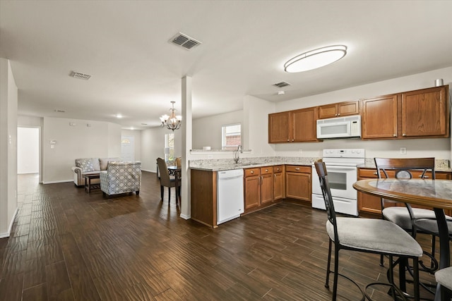 kitchen with sink, dark wood-type flooring, light stone counters, a chandelier, and white appliances