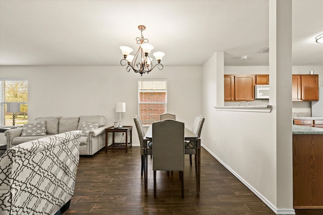 dining space with dark wood-type flooring and an inviting chandelier