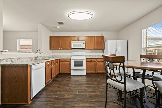 kitchen with light stone countertops, dark hardwood / wood-style flooring, white appliances, and sink