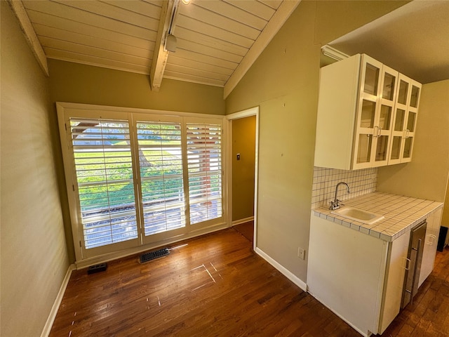 kitchen featuring white cabinets, vaulted ceiling with beams, sink, and dark wood-type flooring