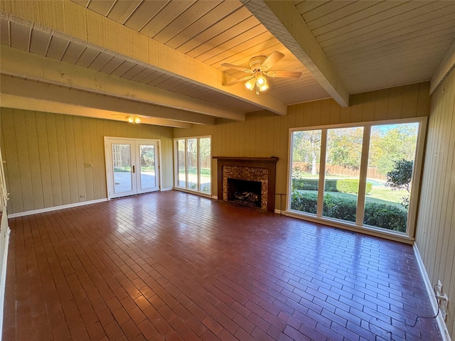 unfurnished living room featuring beamed ceiling, ceiling fan, wood walls, and wood ceiling