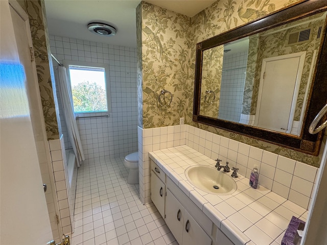 full bathroom with vanity, shower / tub combo with curtain, tile walls, tile patterned flooring, and toilet