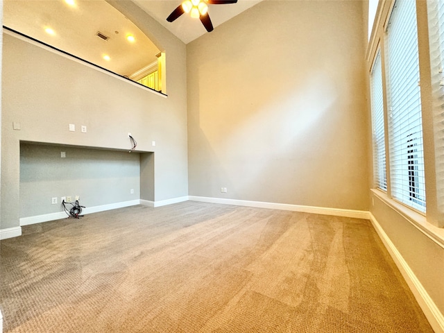 unfurnished living room featuring carpet, ceiling fan, and high vaulted ceiling