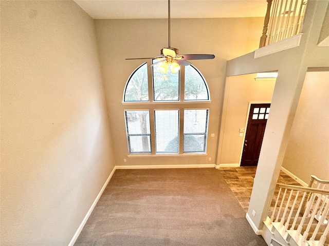 entryway with carpet flooring, ceiling fan, and a towering ceiling