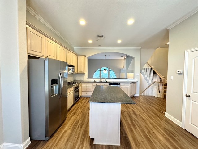 kitchen with light brown cabinets, crown molding, hardwood / wood-style flooring, appliances with stainless steel finishes, and a kitchen island