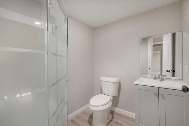 bathroom featuring toilet, vanity, a shower with shower door, and hardwood / wood-style flooring