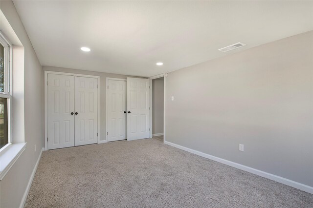 unfurnished bedroom featuring carpet floors and two closets