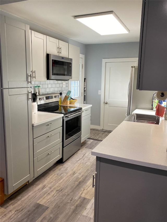 kitchen featuring tasteful backsplash, appliances with stainless steel finishes, sink, and light hardwood / wood-style floors