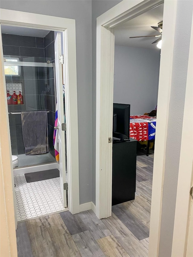 bathroom featuring wood-type flooring, tiled shower, ceiling fan, and toilet