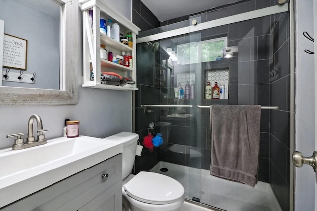 bathroom featuring vanity, a shower with shower door, and toilet