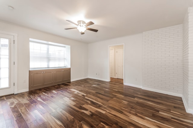 unfurnished room featuring plenty of natural light, brick wall, and dark hardwood / wood-style floors