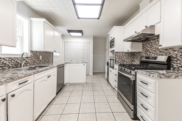 kitchen with light stone countertops, backsplash, stainless steel appliances, sink, and white cabinets