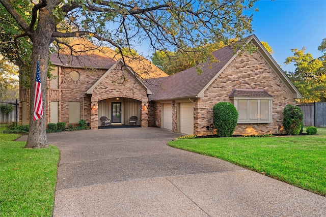 english style home with a garage and a front lawn