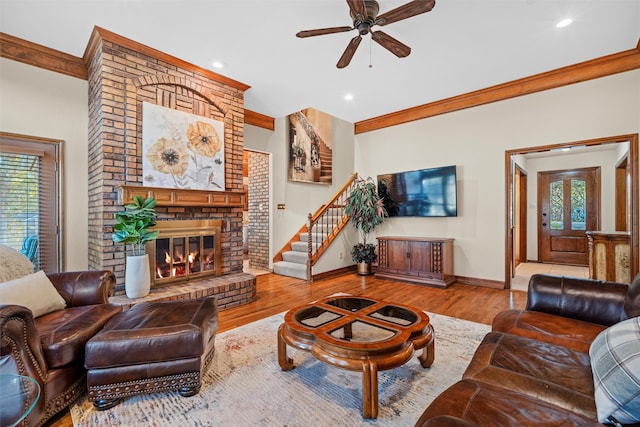 living room featuring a fireplace, light hardwood / wood-style flooring, ceiling fan, and ornamental molding