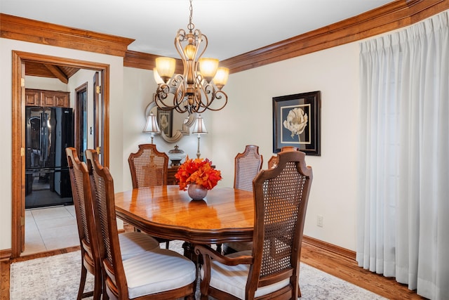 dining space featuring crown molding, light hardwood / wood-style floors, and a notable chandelier