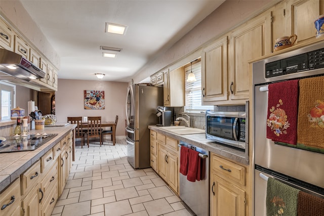 kitchen with backsplash, stainless steel appliances, extractor fan, sink, and tile countertops