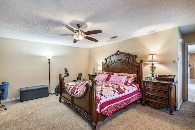 bedroom with ceiling fan, light colored carpet, and a textured ceiling