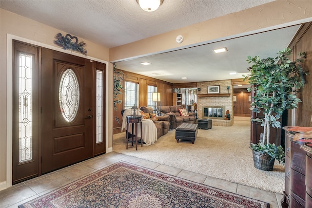 carpeted foyer featuring a fireplace, a textured ceiling, and wooden walls