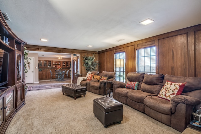 carpeted living room featuring a textured ceiling and wooden walls