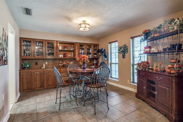 tiled dining room featuring a textured ceiling