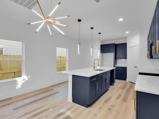 kitchen with blue cabinetry, light hardwood / wood-style flooring, hanging light fixtures, and sink