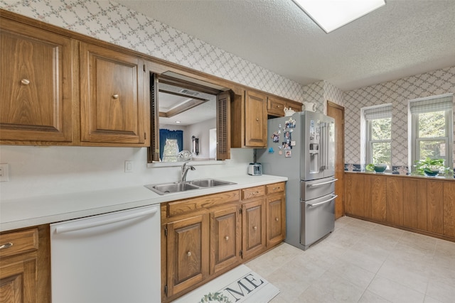 kitchen with a textured ceiling, sink, white dishwasher, and stainless steel refrigerator with ice dispenser