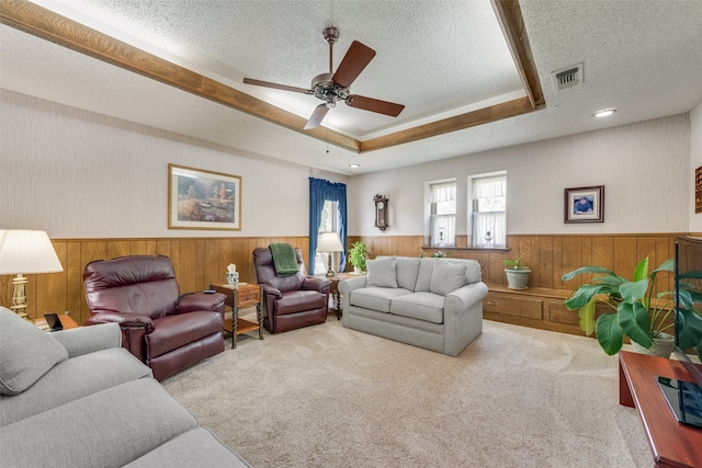 carpeted living room with a textured ceiling, ceiling fan, and wood walls