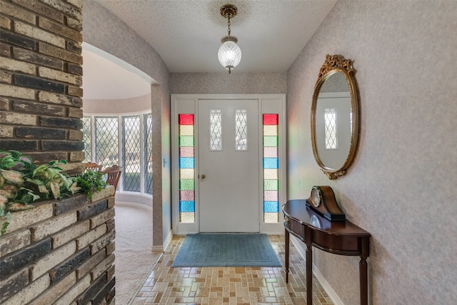 carpeted foyer entrance with a textured ceiling