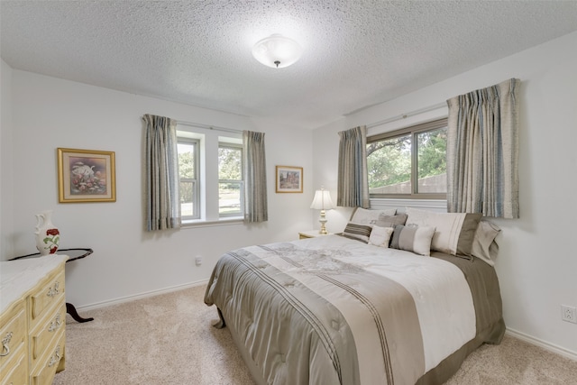 bedroom with light colored carpet and a textured ceiling