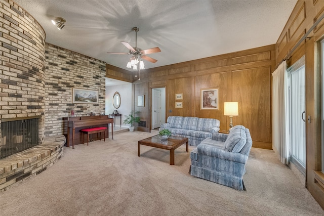 carpeted living room with a textured ceiling, a brick fireplace, ceiling fan, and wood walls