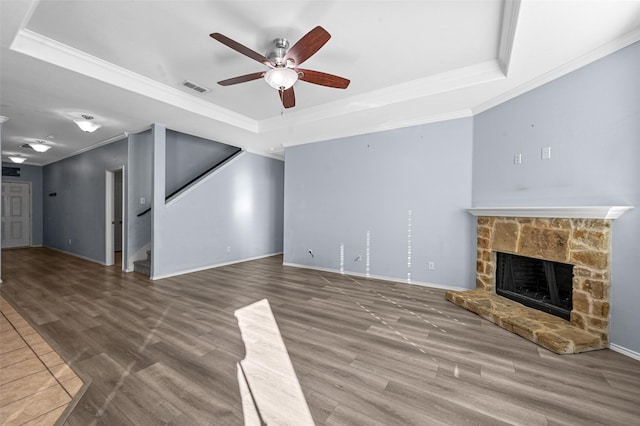 unfurnished living room with hardwood / wood-style floors, a raised ceiling, and crown molding