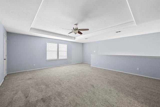 carpeted empty room featuring ceiling fan and a tray ceiling