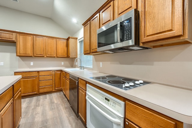 kitchen featuring white appliances, light hardwood / wood-style floors, lofted ceiling, and sink