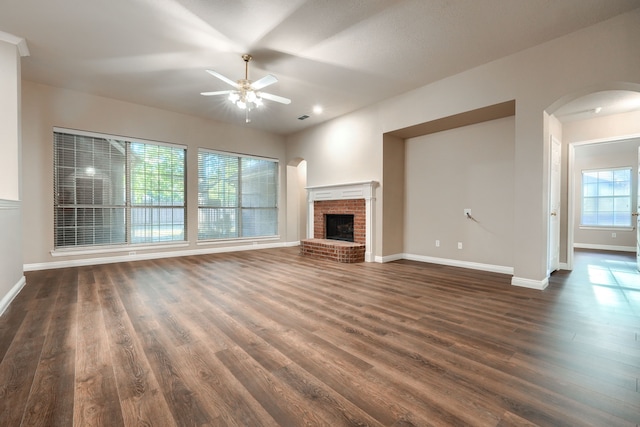 unfurnished living room with ceiling fan, a healthy amount of sunlight, and dark wood-type flooring