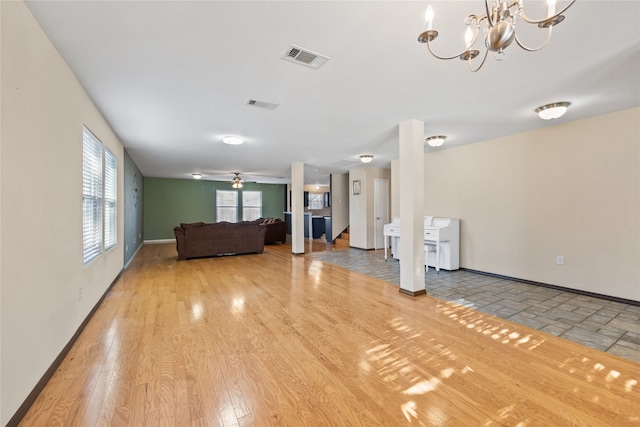 unfurnished living room with ceiling fan with notable chandelier and light hardwood / wood-style flooring