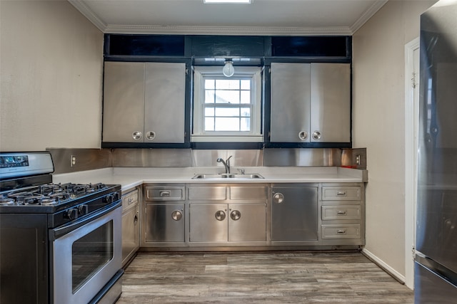 kitchen featuring appliances with stainless steel finishes, light wood-type flooring, ornamental molding, and sink