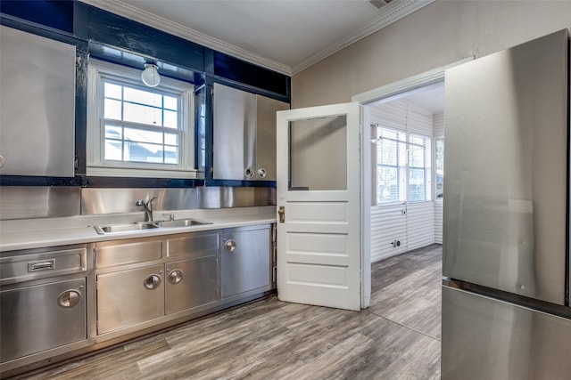 kitchen with stainless steel fridge, ornamental molding, sink, and light hardwood / wood-style flooring