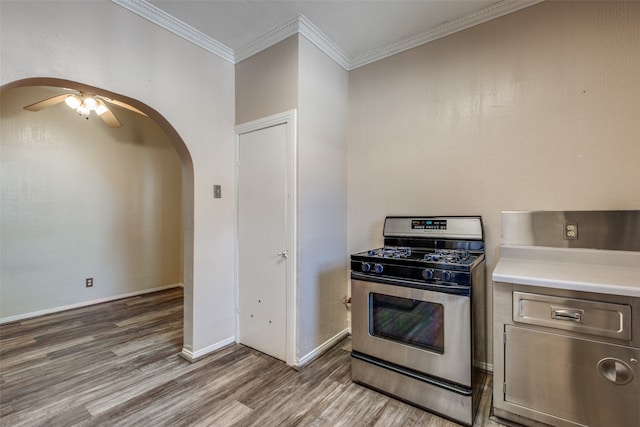 kitchen featuring ceiling fan, ornamental molding, wood-type flooring, and stainless steel gas range