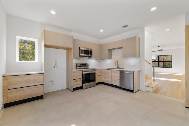 kitchen featuring appliances with stainless steel finishes, light brown cabinetry, ceiling fan, and a healthy amount of sunlight