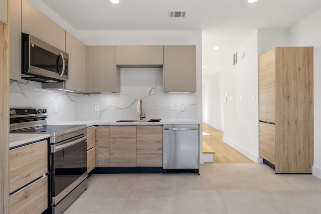 kitchen with decorative backsplash, light brown cabinets, sink, and stainless steel appliances