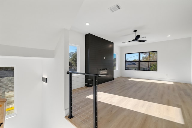 interior space with ceiling fan, a fireplace, and light hardwood / wood-style floors