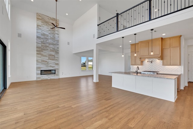 kitchen featuring a fireplace, light wood-style floors, open floor plan, backsplash, and light brown cabinetry