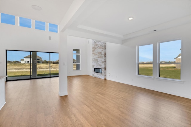 unfurnished living room with beam ceiling, a fireplace, and light hardwood / wood-style flooring