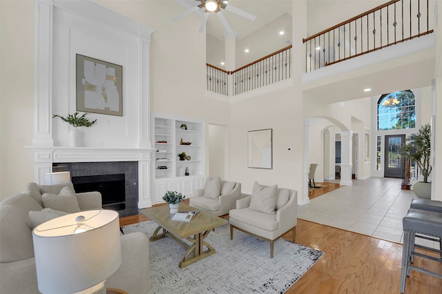 living room with a fireplace, a high ceiling, light hardwood / wood-style floors, and built in features