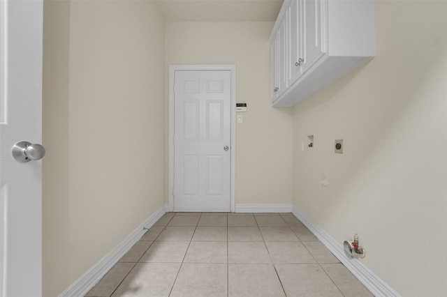 clothes washing area featuring electric dryer hookup, gas dryer hookup, light tile patterned floors, and cabinets