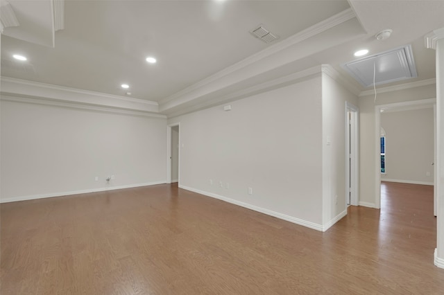 empty room with a tray ceiling, crown molding, and hardwood / wood-style flooring