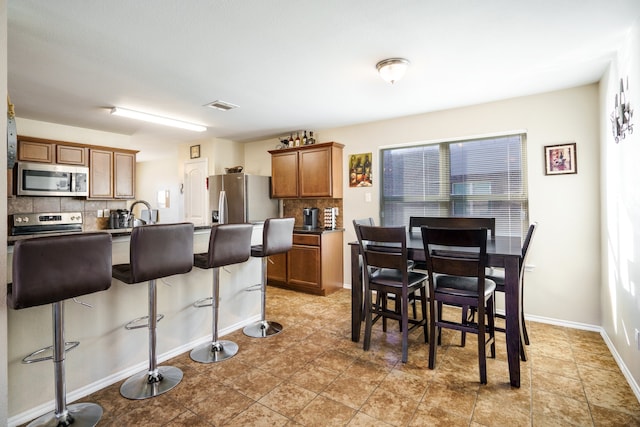 kitchen with appliances with stainless steel finishes, backsplash, and a kitchen breakfast bar